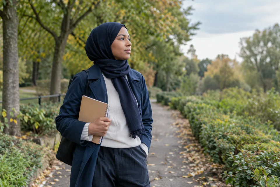 Persoon staat na een wandeling stil op een rustig pad tussen bomen.